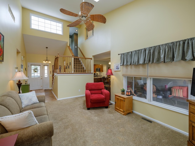 living room featuring visible vents, baseboards, a towering ceiling, and stairs