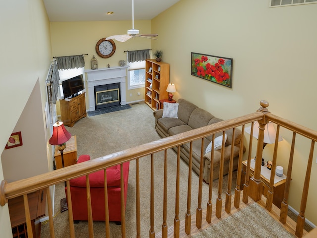 living room with carpet, a ceiling fan, a fireplace with flush hearth, visible vents, and baseboards