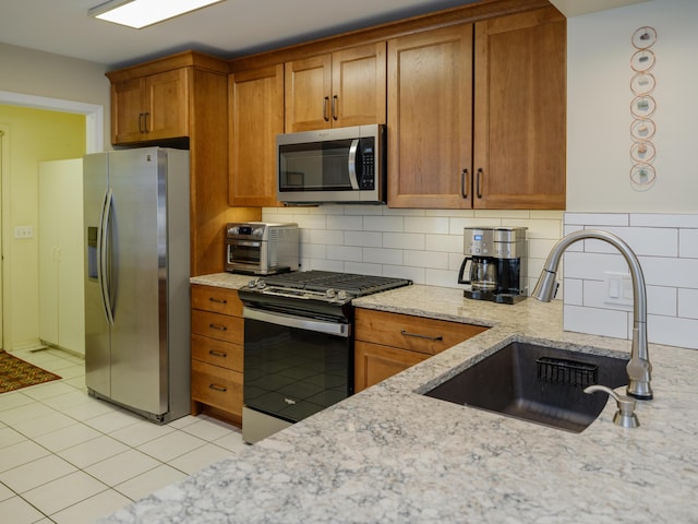 kitchen with appliances with stainless steel finishes, brown cabinetry, and a sink