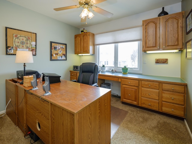home office with dark colored carpet, baseboards, and a ceiling fan