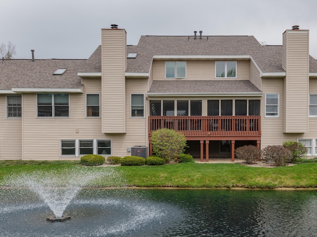 back of property featuring cooling unit, a water view, a chimney, and roof with shingles