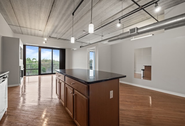 101 Curry Ave Unit 610, Royal Oak, MI 48067 - kitchen featuring dark countertops, a kitchen island, open floor plan, dark wood-style floors, and decorative light fixtures