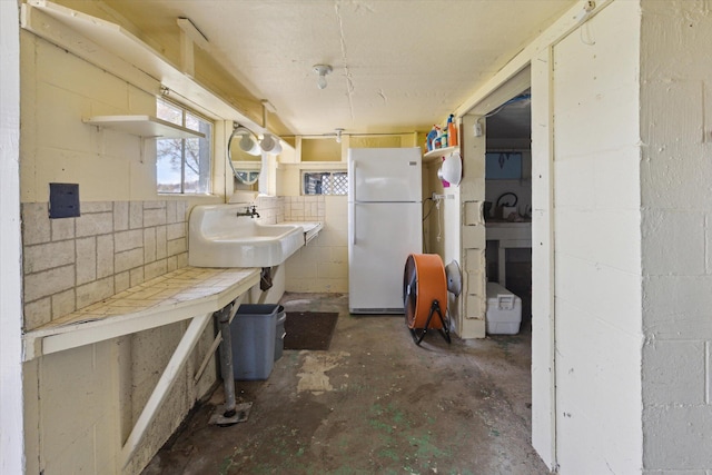 10458 Sleepy Hollow Ln, Mecosta, MI 49332 - kitchen featuring freestanding refrigerator, concrete flooring, concrete block wall, open shelves, and a sink