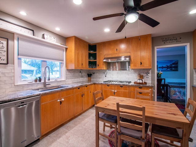kitchen featuring stainless steel appliances, a sink, light stone counters, under cabinet range hood, and recessed lighting