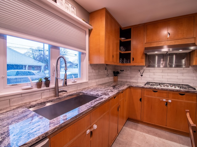 kitchen featuring a sink, stainless steel gas cooktop, stone counters, tasteful backsplash, and light tile patterned floors