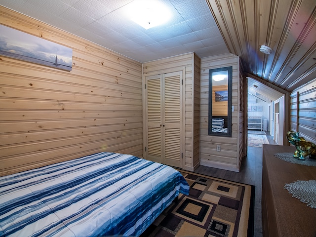 bedroom with wood walls, vaulted ceiling, a closet, and wood finished floors