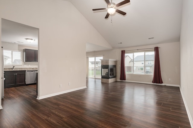 unfurnished living room with a multi sided fireplace, plenty of natural light, ceiling fan, and high vaulted ceiling