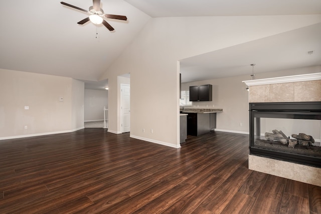 unfurnished living room with high vaulted ceiling, dark wood finished floors, a fireplace, ceiling fan, and baseboards