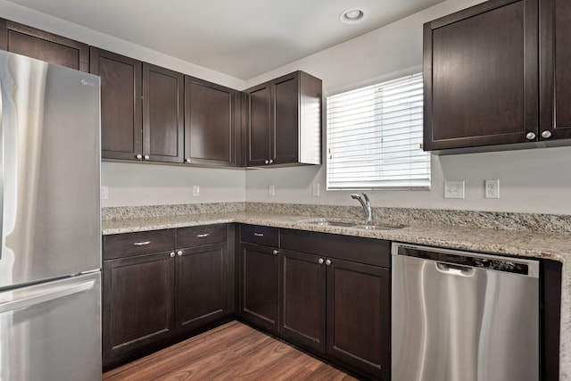 kitchen featuring stainless steel appliances, a sink, dark brown cabinetry, light wood-type flooring, and recessed lighting