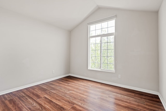 empty room featuring lofted ceiling, baseboards, a healthy amount of sunlight, and wood finished floors