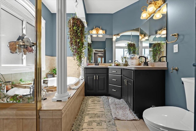 full bathroom featuring toilet, a bath, decorative columns, double vanity, and tile patterned flooring