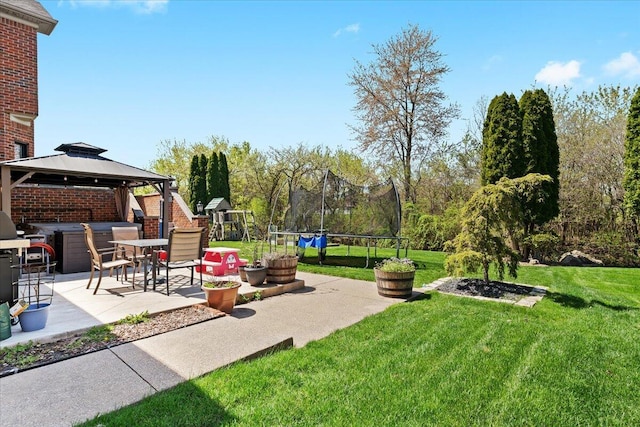 view of grassy yard featuring a trampoline, a patio, a gazebo, and a playground
