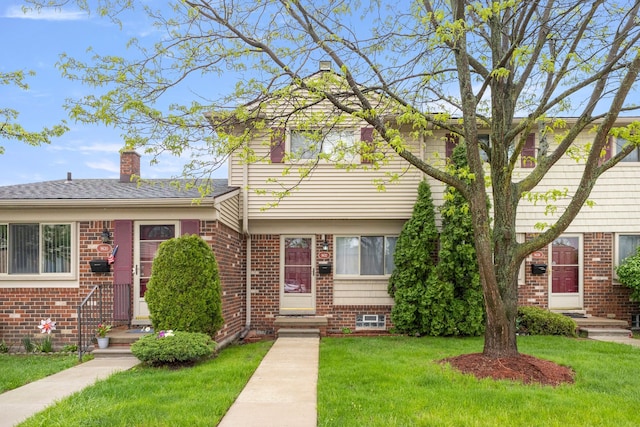 view of front of home with brick siding, a front lawn, and a chimney