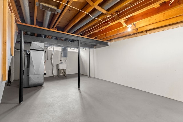 unfinished below grade area with heating unit, electric panel, and a sink