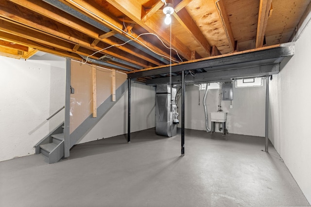 below grade area featuring heating unit, electric panel, a sink, and stairway