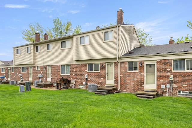 rear view of property with a chimney, entry steps, a yard, and central air condition unit