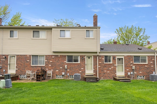 rear view of house featuring entry steps, a chimney, and a yard