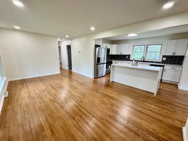 kitchen featuring decorative backsplash, a center island, stainless steel fridge, and light wood-type flooring