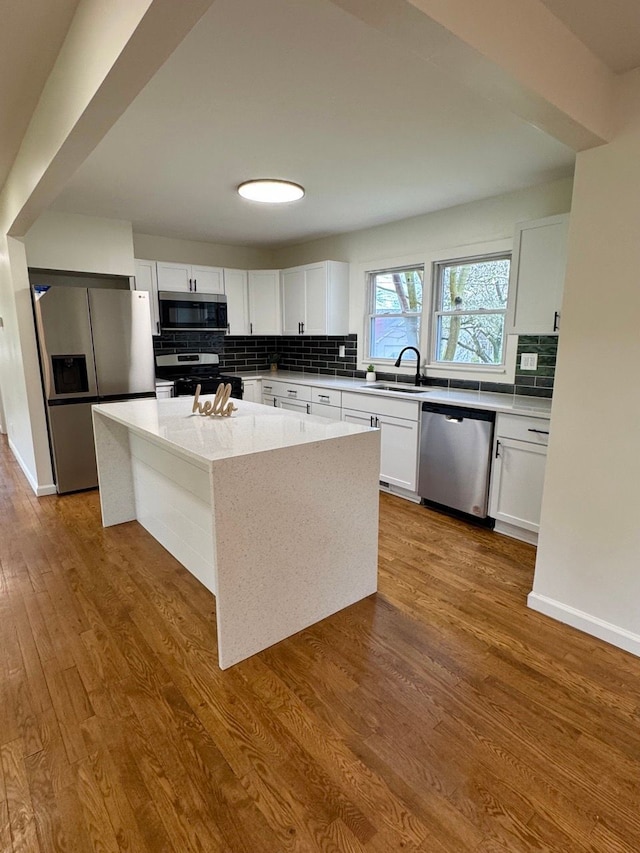 kitchen featuring a sink, white cabinets, appliances with stainless steel finishes, decorative backsplash, and dark wood-style floors