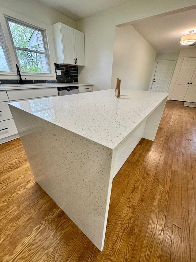 kitchen featuring white cabinetry, a kitchen island, wood finished floors, and a sink