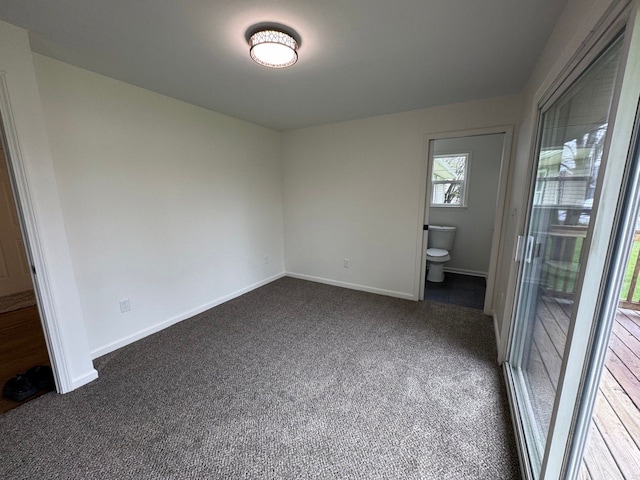 unfurnished bedroom with dark colored carpet and baseboards