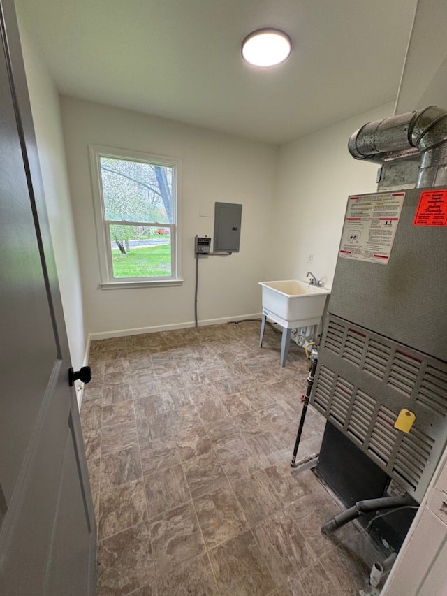 clothes washing area with electric panel, baseboards, and a sink