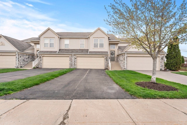 view of property featuring stone siding, a garage, and driveway