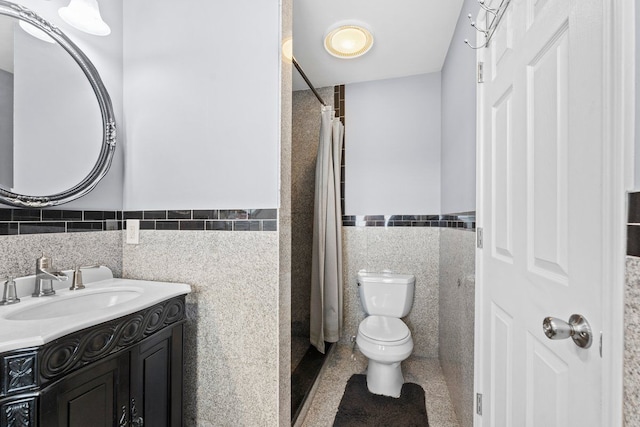 full bathroom with tile walls, toilet, wainscoting, and vanity