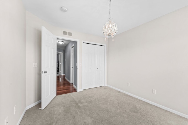 unfurnished bedroom featuring an inviting chandelier, carpet floors, baseboards, and visible vents