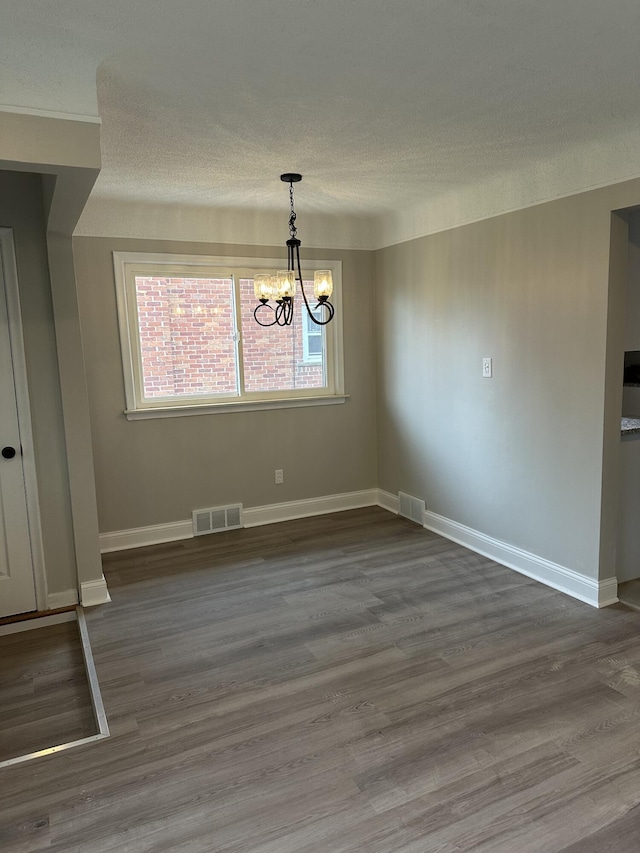 unfurnished dining area featuring a chandelier, a textured ceiling, and visible vents