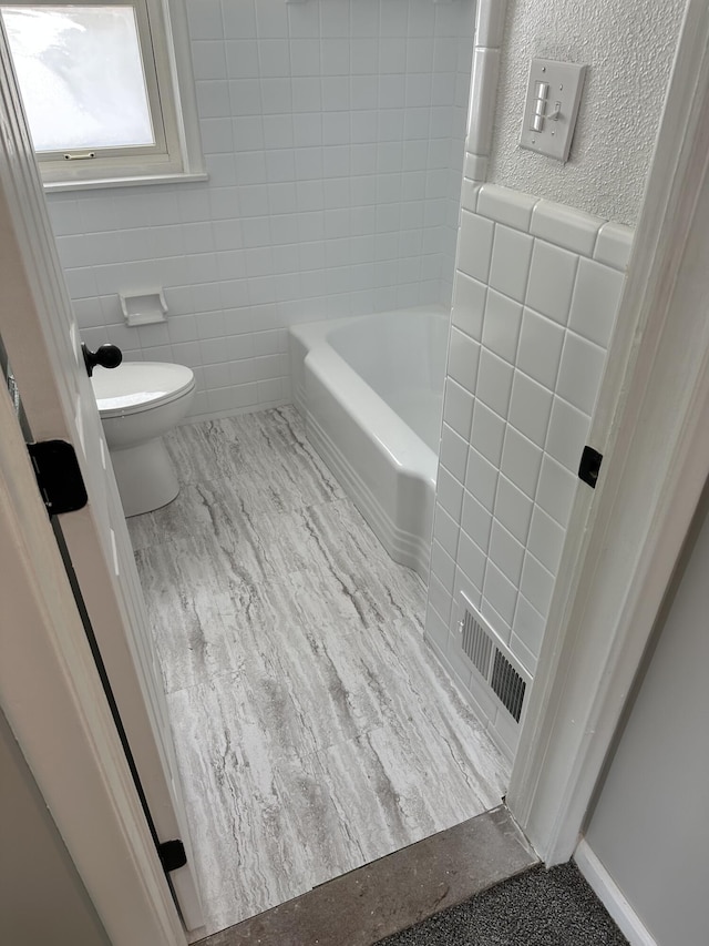 bathroom with tile walls, toilet, and visible vents