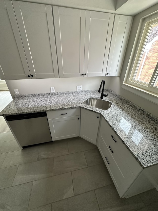 kitchen with white cabinetry, light stone counters, a sink, and dishwasher