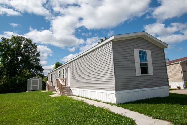 view of side of property featuring a lawn, an outdoor structure, and a storage shed