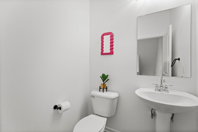 bathroom featuring toilet, baseboards, and a sink