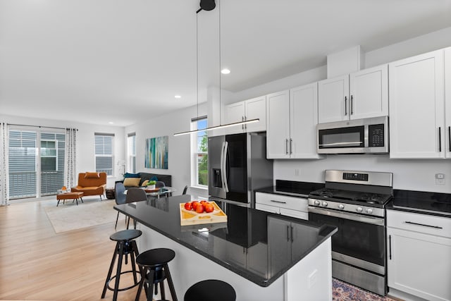 kitchen featuring stainless steel appliances, open floor plan, recessed lighting, a breakfast bar, and white cabinets