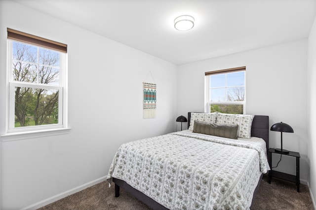 bedroom with dark carpet and baseboards