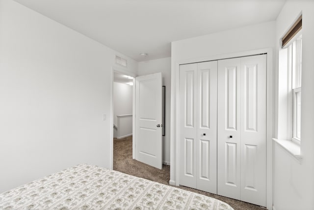 carpeted bedroom featuring multiple windows, a closet, and baseboards
