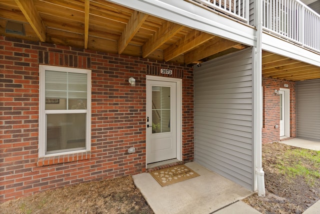 entrance to property with a balcony and brick siding