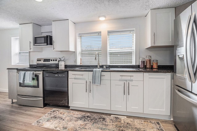 3012 Lansdowne Rd, Waterford, MI 48329 - kitchen featuring appliances with stainless steel finishes, a sink, light wood finished floors, white cabinetry, and a textured ceiling
