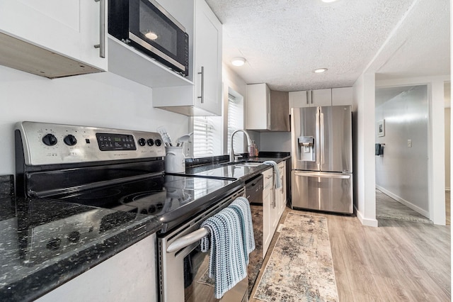 3012 Lansdowne Rd, Waterford, MI 48329 - kitchen featuring appliances with stainless steel finishes, a sink, a textured ceiling, light wood-style flooring, and white cabinetry