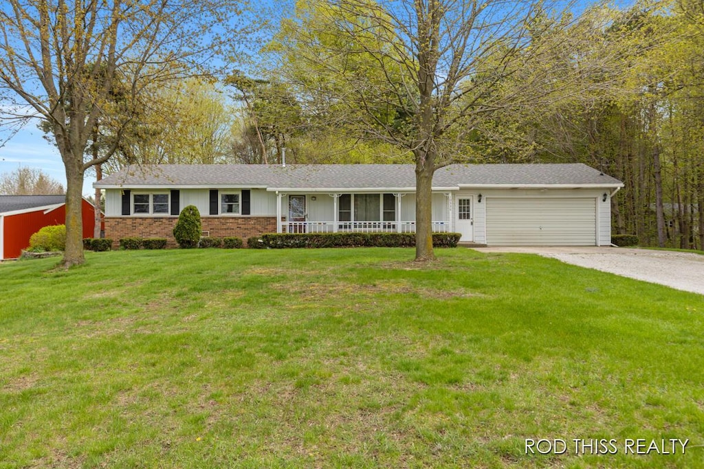 single story home with a porch, an attached garage, brick siding, driveway, and a front yard