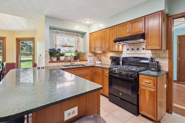 11104 Southbrook Dr, Ceresco, MI 49033 - kitchen with black gas range oven, a sink, under cabinet range hood, a peninsula, and brown cabinetry