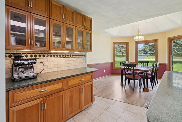 11104 Southbrook Dr, Ceresco, MI 49033 - kitchen featuring brown cabinets, a chandelier, glass insert cabinets, decorative light fixtures, and backsplash