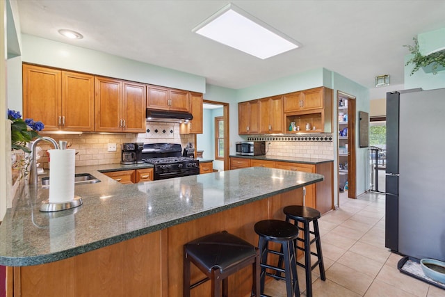 11104 Southbrook Dr, Ceresco, MI 49033 - kitchen featuring stainless steel appliances, a sink, under cabinet range hood, a peninsula, and brown cabinetry