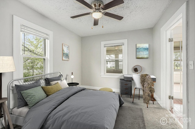 carpeted bedroom with a textured ceiling, baseboards, and a ceiling fan