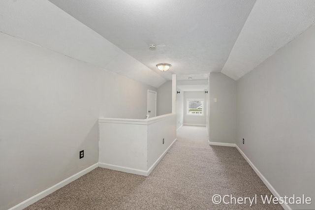 corridor with carpet flooring, baseboards, and lofted ceiling