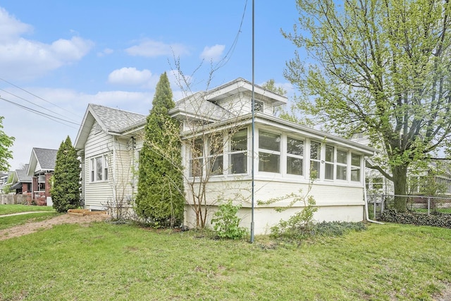 view of side of property with a yard, a sunroom, and fence
