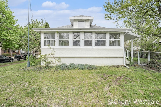 view of front of home featuring a gate, roof with shingles, fence, brick siding, and a front lawn