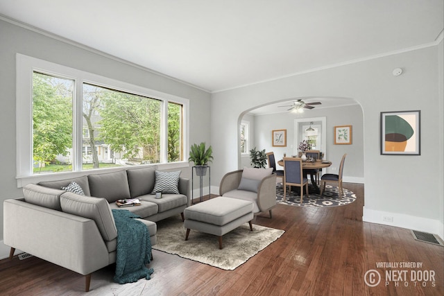 living area with arched walkways, baseboards, visible vents, and dark wood finished floors