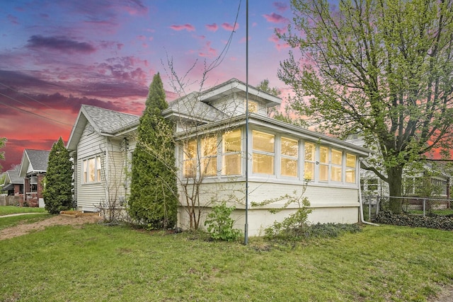 property exterior at dusk with a yard and fence